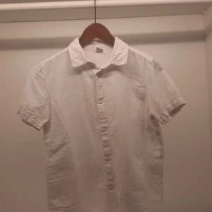 Vit kortärmad skjorta från Lindex - Säljer en stilren vit kortärmad skjorta från Lindex. Skjortan har klassisk krage och knappar framtill. Perfekt för en avslappnad och snygg look. Passar barn i åldern 10-12 år.