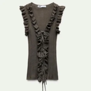 Brun ribbad topp från Zara - Snygg brun ribbad topp från Zara med volangdetaljer längs ärmarna och en knytning framtill. Perfekt för en stilren look.