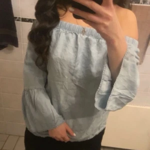 Ljusblå offshoulder blus - Säljer en söt ljusblå offshoulder blus med långa ärmar. Perfekt för en avslappnad och stilren look. Blusen har en elastisk kant upptill för en bekväm passform. Oanvänd