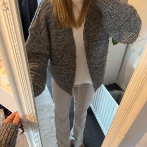 Grå stickad kofta - Mysig grå stickad kofta med långärmad design. Perfekt för kyligare dagar och ger en avslappnad look. Koftan har en enkel och stilren stil som passar till många olika outfits.