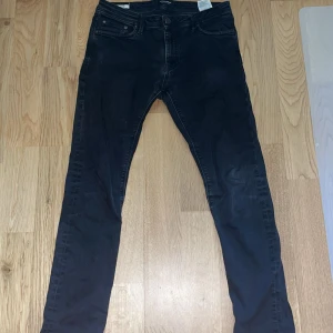 Svarta slim jeans från Jack & Jones - Snygga svarta slim jeans från Jack & Jones, modell Glenn. De har en klassisk femficksdesign och en knappgylf. Perfekta för en stilren look.
