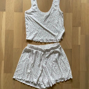 Vit linne med hjärtmönster - Säljer en söt vit linne med små röda hjärtan. Linnet har breda axelband och en rund halsringning. Den är ca men skulle säga att den kanske var S i längd