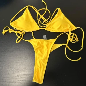 Bikini - Snygg gul bikini med trekantsöverdel och knytband. Perfekt för soliga dagar på stranden. Underdelen har en enkel design med smala band för en stilren look.
