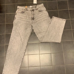 Grå jeans från Woodbird - Snygga grå jeans från Woodbird med en klassisk femficksdesign. De har en dragkedja och knapp framtill. Jeansen är helt nya. Med lappar kvar. Storlek 32/32. Nypris 999 kr.