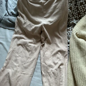 Beige randiga byxor xs - Snygga beige byxor med diskret randigt mönster. Perfekta för en stilren look. Byxorna har en normal passform och är tillverkade i ett bekvämt material.