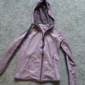 Ljuslila träningsjacka - Säljer en snygg ljuslila träningsjacka men luva och snygga detaljer! Endast använd fåtal gånger!