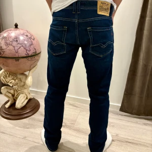 Mörkblå jeans från Replay - Snygga mörkblå jeans från Replay med klassisk femficksdesign och en bekväm passform. Perfekta för en stilren look. Märkeslappen syns tydligt på baksidan.