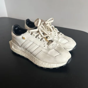 Vita sneakers från Adidas - Snygga vita sneakers från Adidas med klassiska ränder på sidan. Skorna har en bekväm sula och snörning framtill. Perfekta för en stilren look.