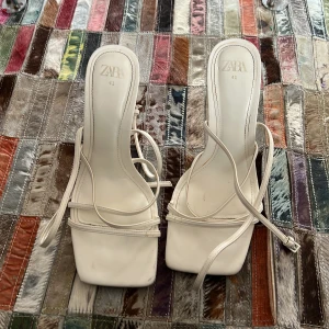 Vita klackskor från Zara - Snygga vita klackskor från Zara med smala remmar och fyrkantig tå. Perfekta för en elegant look.
