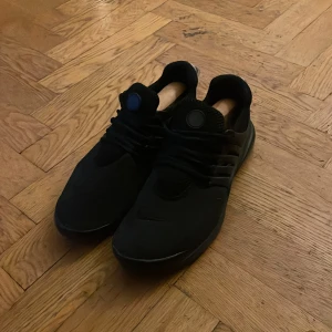 Nike presto  - Snygga svarta sneakers med snörning och en stilren design. Skorna har en låg profil och är perfekta för en avslappnad stil. De har en diskret detalj på hälen och en bekväm passform.