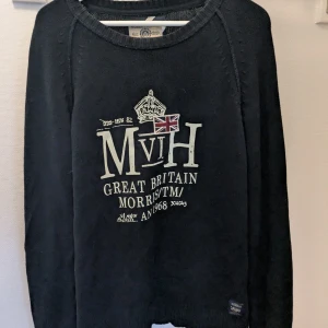 Svart tröja från Morris Gent's - Säljer en svart tröja från Morris Gent's med tryck på framsidan som inkluderar text och en brittisk flagga. Tröjan har långa ärmar och en rund halsringning. Perfekt för en stilren och avslappnad look.
