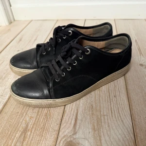 Svarta sneakers med snörning - Snygga svarta sneakers från märket lanvin med snörning och vit sula. Skorna har en stilren design med rund tå och är perfekta för en avslappnad look. Tillverkade i skinn för en hållbar och bekväm passform. Pris kan diskuteras vid snabb affär.