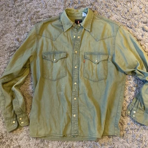 Levi's Jeans Skjorta - Säljer en grön långärmad skjorta från Levi's, som är köpt i Japan, i storlek M/L. Liten reva på nedre höger ärm annars fint skick, skriv vid fler frågor!