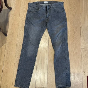 Grå jeans från Wrangler W31 L32 - Snygga grå jeans från Wrangler med klassisk femficksdesign. De har en dragkedja och knapp framtill. Perfekta för en avslappnad stil.