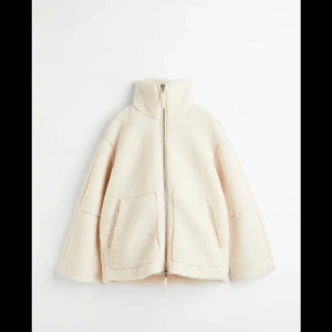 Vit teddyjacka med dragkedja - Mysig vit teddyjacka med hög krage och dragkedja framtill. Jackan har två stora fickor och en avslappnad passform, perfekt för kyliga dagar. Den fluffiga texturen ger en trendig look. Från hm i storlek S. Lite smink längst upp vid kragen men inget som syns jätte mycket 