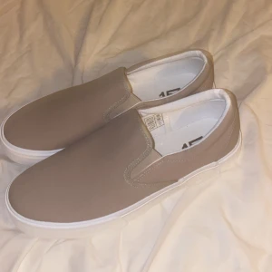 Beige slip-on sneakers - Snygga beige slip-on sneakers från 157 med vit sula. Perfekta för en avslappnad stil. Skorna har en enkel design utan snörning och en bekväm passform.