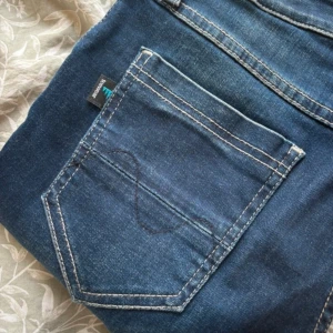 Mörkblå jeansbyxor - Snygga mörkblå jeansbyxor med klassisk femficksdesign och kontrastsömmar. Perfekta för en avslappnad stil. De har en knapp och dragkedja framtill.