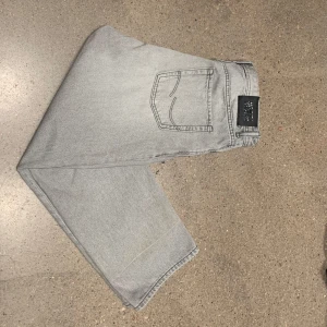  Jack & Jones jeans grå 158 - Säljer ett par stilrena grå jeans från Jack & Jones med klassisk femficksdesign. NYPRIS:600.🤩🍾                De har en rak passform och är perfekta för en avslappnad stil. Tillverkade i slitstarkt denim med en stilren look. Priset är ej skrivet i sten.  Hör av dig vid minsta fundering💭           
