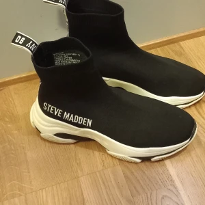 Svarta sneakers från Steve Madden - Snygga svarta sneakers från Steve Madden med vit sula och logotyp på sidan. Använt vid max 3 tillfällen 