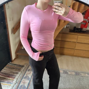 Rosa långärmad topp - Säljer en snygg rosa långärmad topp i tight passform. Perfekt för en stilren och bekväm look. Passar bra till både jeans och kjol. Hör av dig vid intresse!