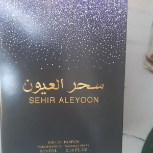 Sehir Aleyoon Eau de Parfum - Elegant Eau de Parfum från Sehir Aleyoon med en stilren flaska och en förpackning dekorerad med gnistrande detaljer. Tillverkad i Förenade Arabemiraten, denna parfym erbjuder en lyxig doftupplevelse. Flaskan rymmer 2.38 FL.OZ och har en svart kork. Helt ny, endast öppnad för att lukta på och tyvärr passa den ej mig.