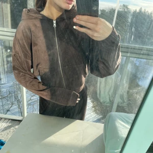 Brun hoodie med dragkedja med matchande mjukis byxor  - En brun hoodie med dragkedja och luva som kommer från bikbok storlek S. Byxorna kommer från Gina tricot men färgen är ungefär detsamma. Dem är i storlek S och jag är 160 cm. Kan sälja för sig också🥰 bara byxor kostar 70 och tröjan 70. För båda 130