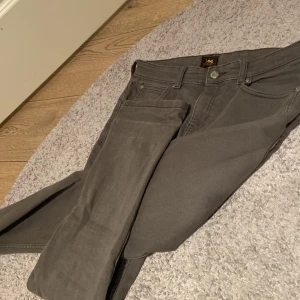 Grå jeans från Lee - Snygga grå jeans från Lee med klassisk femficksdesign och knappgylf. Perfekta för en stilren look. Märkeslogga på bakfickan och bältesslingor i midjan.   (14-15 år) 