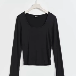 Soft touch långärmad topp - Snygg svart långärmad topp från Gina Tricot med djup rund halsringning. Perfekt för en stilren look och kan enkelt matchas med jeans eller kjol. Endast testad.