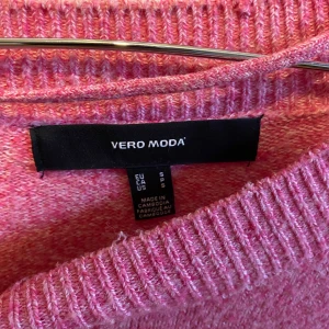 Rosa stickad tröja från Vero Moda - Säljer en mysig rosa stickad tröja från Vero Moda. Tröjan har en rund halsringning och långa ärmar, perfekt för kyligare dagar. Den är enkel och stilren, vilket gör den lätt att matcha med olika outfits. Perfekt för både vardag och lite finare tillfällen.