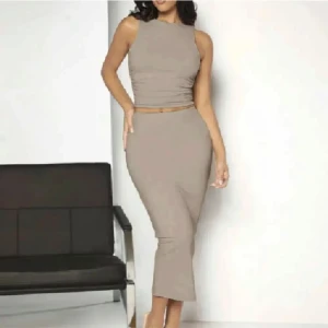 Beige ärmlös klänning - Snygg beige klänning med ärmlös design och tight passform. Klänningen har en elegant lång längd som passar perfekt för olika tillfällen. Den är tillverkad i ett mjukt och bekvämt material.