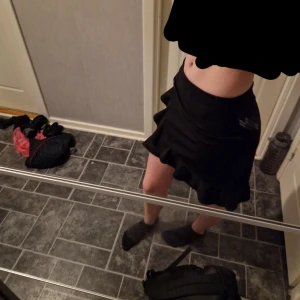 Svart kjol med volang - Snygg svart kjol med volangdetaljer. Perfekt för en stilren look. Kjolen har en kort längd och är i en klassisk svart färg. Köpt här på plick men den kom tyvärr inte till användning så säljer den vidare.