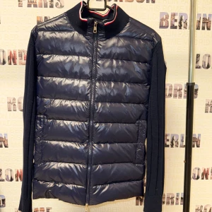 Jacka - Snygg mörkblå jacka med quiltad framsida och stickade ärmar. Jackan har en dragkedja framtill och en ribbad krage med röd och vit rand. Perfekt för kyligare dagar. Säljer då den ej passar mig. Priset kan diskuteras vid smidigare affär