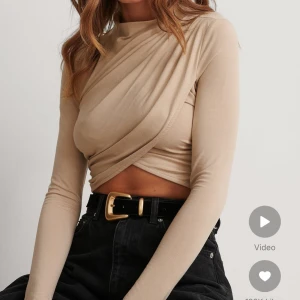 Beige omlottopp - Snygg beige omlottopp med lång ärm och croppad design. Perfekt för en stilren look med en twist. Toppen har en elegant omlottdetalj framtill som ger en unik touch. Skriv för bild på min topp. 