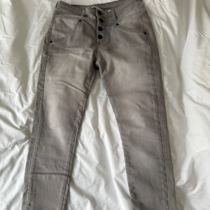 Grå byxor från House of Lola - Snygga grå jeans i jättefint skick från House of Lola i stretchigt material. Endast använda vid ett par tillfällen. Jag är 1,63 lång och byxorna är lagom långa ner till hälen med medelhög midja.
