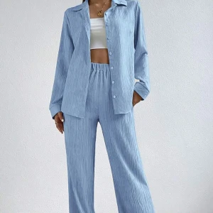 Ljusblått set med skjorta och byxor - Snyggt ljusblått set med en långärmad skjorta och matchande byxor. Skjortan har knappar framtill och byxorna har en elastisk midja för extra komfort. Materialet är ribbat vilket ger en trendig look. Perfekt för en avslappnad stil.