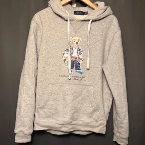 Ralph Lauren Hoodie - Grå Ralph Lauren Polo Bear hoodie i storlek L, men sitter mer som en M. Skick: 7/10, lite har lossnat från trycket. Skriv vid frågor och funderingar!