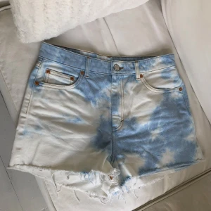 Jeans shorts - Ett par jättefina jeansshorts från Monki i storlek 28 med moln/vit och blå fläckar som mönster 🥰 Endast använd någon gång, passar mig som brukar ha S/M. Säljer även linnet i bilderna!