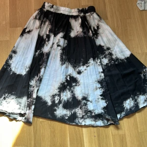 Svart och vit kjol från Bik Bok - Säljer en superfin svart och vit kjol från Bik Bok. Den har ett coolt batikmönster och är plisserad för en snygg look. Perfekt för både vardag och fest! 🖤🤍