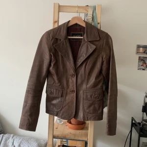 Brun läderjacka - Säljer en snygg brun läderjacka/kavaj från Gianini i storlek 36 men skulle säga att den är liten i storleken. Använt skick men utan skador, skulle säga att den har en fin patina! ❤️De orginala extraknapparna finns i innerfickan!