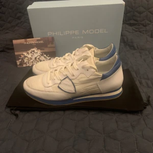 Vita och blå sneakers från Philippe Model - Säljer ett par snygga vita sneakers från Philippe Model med blå detaljer. Modellen är Philip model trpx. Allt som är med på bilden ingår✅ Om ni har några frågor eller fungerar så är det bara att skriva ✉️