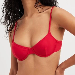 Röd bikiniöverdel - Säljer en snygg röd bikiniöverdel med justerbara axelband. Den har en enkel och stilren design, perfekt för sommardagar på stranden eller vid poolen. Materialet känns mjukt och bekvämt mot huden.