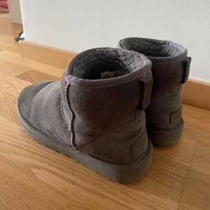 Gråa Uggs  - Säljer mina 2 gråa uggs, storlek 38, de är använda 2 vintrar, färgen på framsidan är lite skadad av vatten annars är det inga fel på de💕💕