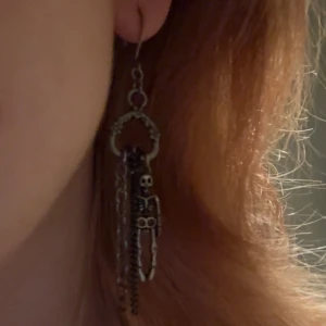 Skelettörhängen - Silverfärgade örhängen som har flera hängande kedjor och föreställer skelett. Det ena skelettet är lite missfärgat (se bild 2) men det syns inte när man har på sig dem. Köpt här på Plick men säljer då de inte är riktig min stil längre. Pris kan diskuteras