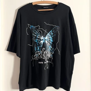 Graphic t-shirt - Svart t-shirt med blått tryck! Tröjan har en oversized passform. Har använts fåtal gånger, inga märken eller fläckar! Alla använda plagg tvättas noga innan leverans! Det är bara att skriva om du har några frågor! <3