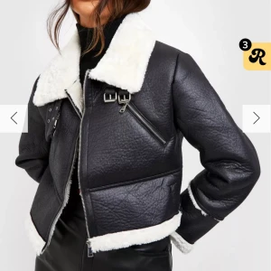 Svart skinnjacka med vit pälsdetalj - Snygg svart skinnjacka med vit pälsdetalj på krage och ärmslut. Jackan har dragkedja och spännen vid kragen för extra stil. Perfekt för att hålla värmen med en cool look. Den är i storlek 36 och bara använd fåtal gånger men ser ut som ny