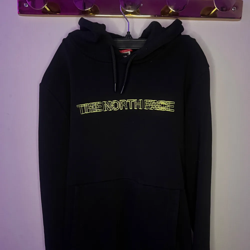 Säljer en svart hoodie från The North Face med logga både fram och bak. Hoodien har en klassisk design med dragsko i huvan och en stor ficka framtill. Perfekt för en avslappnad stil.. Neuletakit & Villapaidat.