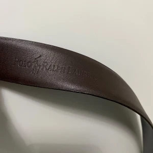 Svart skärp från Polo Ralph Lauren - Snyggt svart skärp från Polo Ralph Lauren i skinn. Skärpet har en stilren design med en silverfärgad spänne. Perfekt för att ge en klassisk touch till din outfit. Svart på utsidan och brunt på insidan. Ny köpt för 1100 men säljer för ett jätte bra pris.