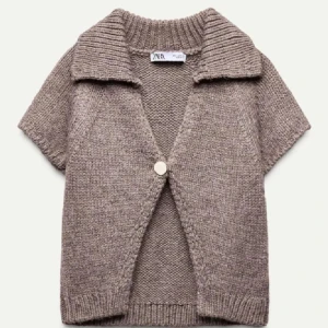 NYSKICK! Beige stickad kofta från Zara - Säljer en mysig beige stickad kofta från Zara med korta ärmar och en stor knapp framtill. Den har en ribbad krage och nederkant. Koftan är helt oanvänd. 
