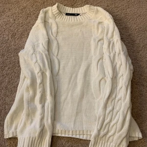 Vit stickad tröja från 157 - Säljer en vit stickad tröja från 157 med kabelstickat mönster. Tröjan har långa ärmar och ribbade muddar vid ärmslut. Storlek S