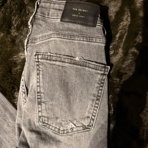 Grå skinny jeans från Zara - Snygga grå skinny jeans från Zara med slitna detaljer och råa kanter vid bensluten. Perfekta för en trendig look. De har en klassisk femficksdesign och knappgylf.